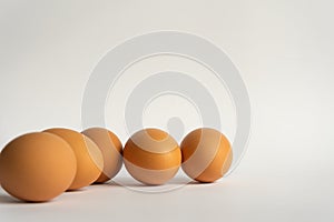 Five fresh brown chicken eggs in a row diagonally on grey background. Easter holiday