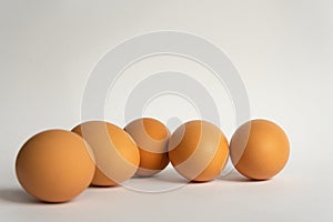 Five fresh brown chicken eggs in a row diagonally on grey background. Easter holiday