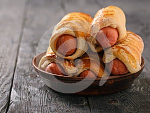 Five fresh, homemade pigs in a blanket on the black wooden table