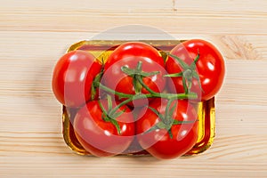 Five fresh red tomatoes with green stem in the tray , isolated on the background