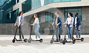 Five friends having pleasant ride on motorized kick scooters