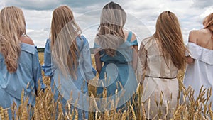 Five girls with long blond hair in a field of golden wheat.