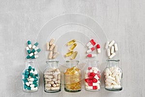 Five glass bottles of supplements pills. Variety of nutritional supplements and vitamin capsules.