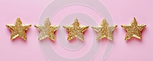 Five gold glitter stars on a pink background