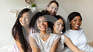 Five gorgeous young happy girls smiling posing seated in bed