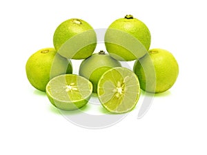 Five green limes in pyramid stacking and two splitted halves on white background.