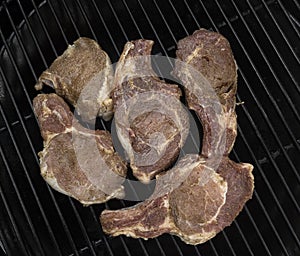 Five half-roasted pork chops on a gas grill