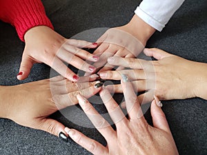 five hands of women to the center as a sign of cooperation and teamwork