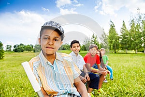 Five happy children sit on chairs in row outdoors