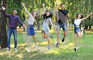 Five happy friends young women and men jumping outdoors