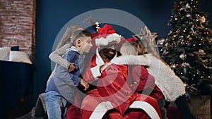 Five happy kids hugging santa claus.