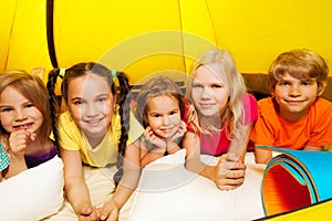 Five happy kids laying in tent and smile