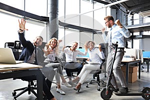 Five happy modern business people are keeping arms raised and expressing joyful while sitting in large office.