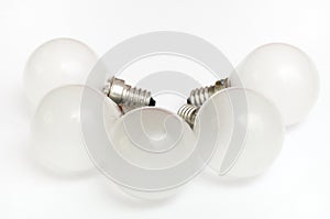 Five identical white glass light bulbs arranged neatly white backdrop