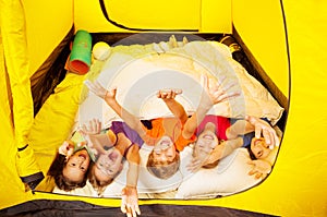 Five kids lay covered with blanket in a tent