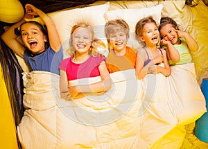 Five kids lay under blanket