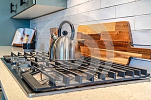 Five knobs kitchen cooktop with kettle over the burners and cast iron grate