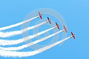 Five light engine airplane perform aerobatics in a cloud of smoke