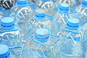 Five-liter plastic drinking water bottles close-up, soft focus
