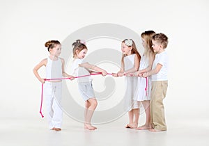 Five little children in white clothes draw over rope.