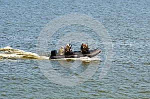 Five military men with weapons and special equipment in the black motor boat. Special operations forces
