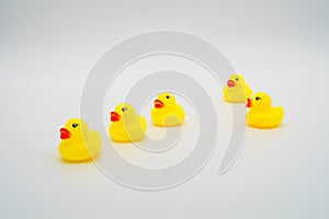 Five mini yellow rubber ducks in a row. One duck making their wa