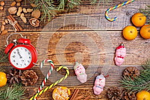 Five minutes before the new year. Cozy wooden background Christmas sweets and toys pigs. View from above.