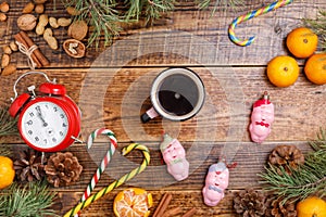 Five minutes before the New Year and a cup of coffee. Cozy wooden background Christmas sweets and toys pigs.