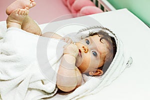 Five month baby wearing towel after bath. Childhood and baby care concept