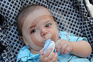 Five months old baby boy playing in the pushchair