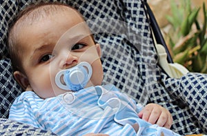 Five months old baby boy playing in the pushchair