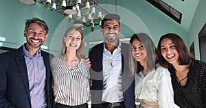 Five motivated and enthusiastic multiethnic workmates smile looking at camera