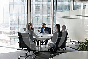 Five multi ethnic business people negotiating in modern boardroom