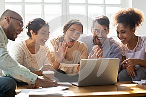 Five multi-ethnic friends make videocall looking at laptop screen photo