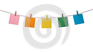 Five multicolored paper blank notes hanging on the rope with wooden clothespins isolated on white