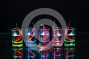 Five multicolored shot glasses full of drink and with the red ch