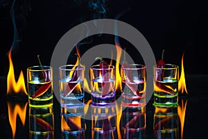 Five multicolored shot glasses full of drink and with the red ch