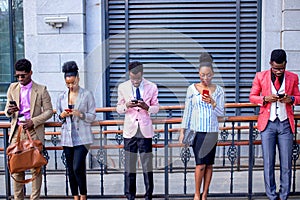 Five office workers standing with mobiles phones and typing sms to each other