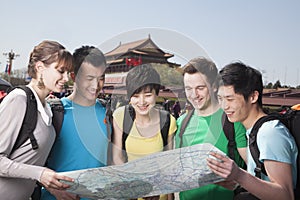 Five people looking at map with Tiananmen Square in background.