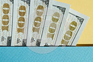 Five pieces of 100 dollar bills on the yellow and blue background. Conceptual photo, minimalistic design of United