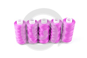 Five pink or magenta sewing threads in a row on a white background