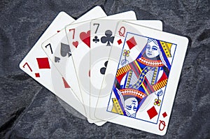 Five playing card`s A hand of a four of a kind seven`s and a queen
