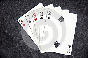 Five playing card`s a hand of a four of a kind three`s and a two