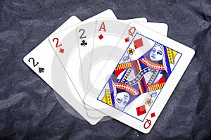 Five playing card`s a hand of a three of a kind two`s and a ace and a queen