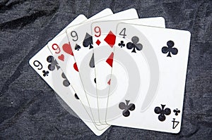 Five playing cards four of a kind nine`s and a four