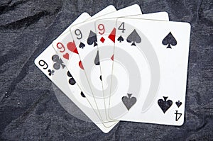 Five playing cards four of a kind nine`s and a four