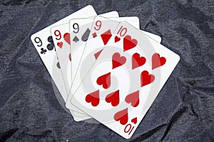 Five playing cards four of a kind nine`s and a ten