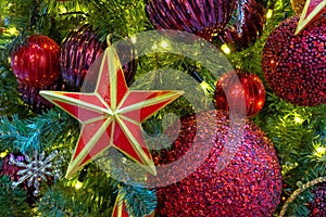 Five-pointed red star with a golden border on the Christmas tree with garlands.