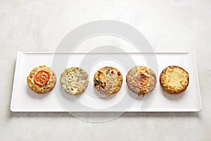 Five quiches on a white plate