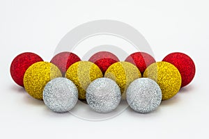 Five red, four yellow and three silver Christmas baubles, lies in a row isolated on a white background with a clipping path and co